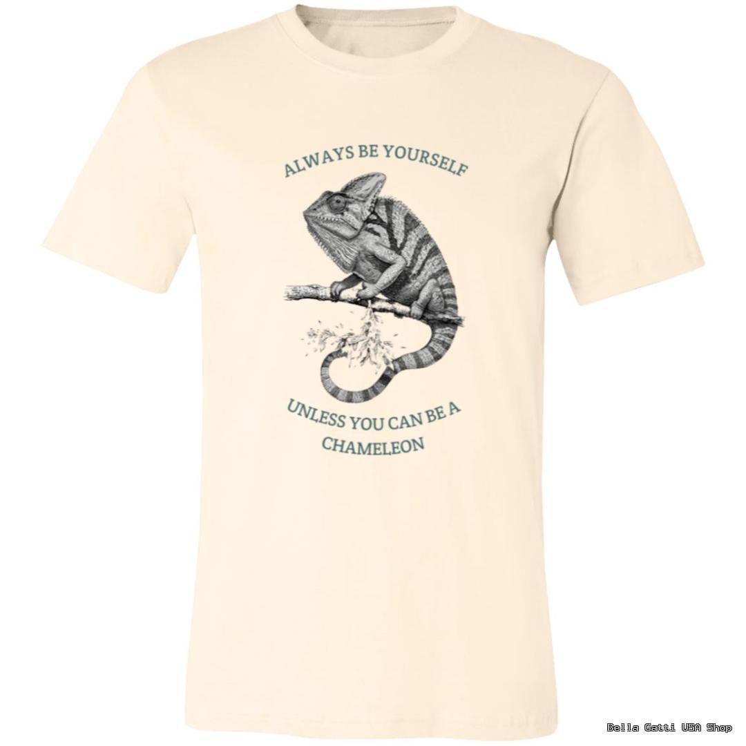 A cream-colored T-shirt features a detailed black-and-white illustration of a chameleon on a branch. Above the chameleon, text reads “ALWAYS BE YOURSELF,” and below, “UNLESS YOU CAN BE A CHAMELEON.” The design is centered on the chest.