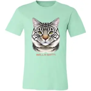 A mint green t-shirt features a realistic illustration of a gray tabby cats face, with green eyes and pink ears. Below the cat’s face, the words “BELLA GATTI” are printed in bold, light red capital letters.
