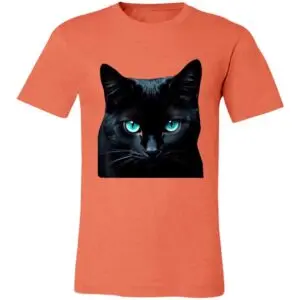 A coral-colored T-shirt features a vivid, square image of a black cat with bright blue, piercing eyes seen from the front. The cats intense gaze and glossy fur contrast sharply against the shirts solid background.