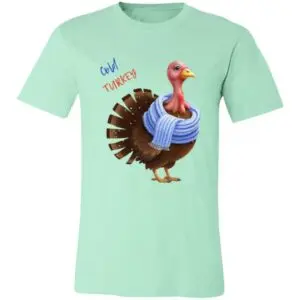 A mint green T-shirt features a cartoon turkey wearing a blue knit scarf. Above the turkey, the words Cold Turkey are written in blue and red. The design is playful and humorous, matching the phrase with the bundled-up bird.