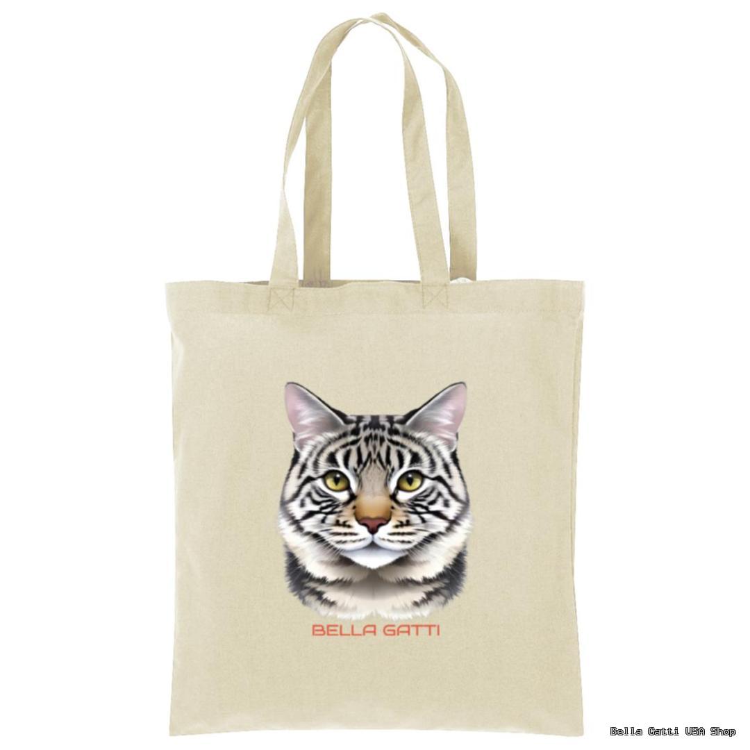 A beige tote bag features a realistic illustration of a gray tabby cat’s face with yellow eyes. Below the cat’s face, the words “BELLA GATTI” are printed in red uppercase letters. The background is plain white.