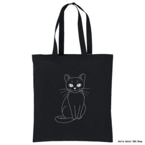 A black tote bag features a simple white line drawing of a seated cat, facing forward with its tail curled around its body. The cat has large eyes and long whiskers. The background is plain white.
