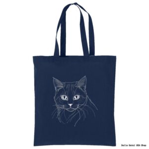 A navy blue tote bag featuring a minimalist white line drawing of a cats face with expressive eyes and detailed fur. The bag has two long handles for carrying and a plain background, highlighting the simple yet elegant cat illustration.