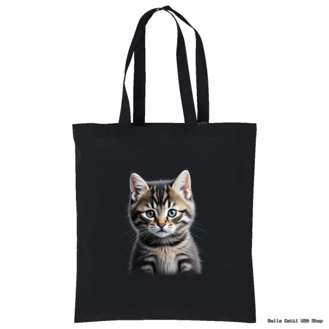 A black tote bag with two handles features a realistic print of a gray tabby kitten with white markings, bright eyes, and perky ears centered on the front. The background is plain, making the kitten the focus of the design.