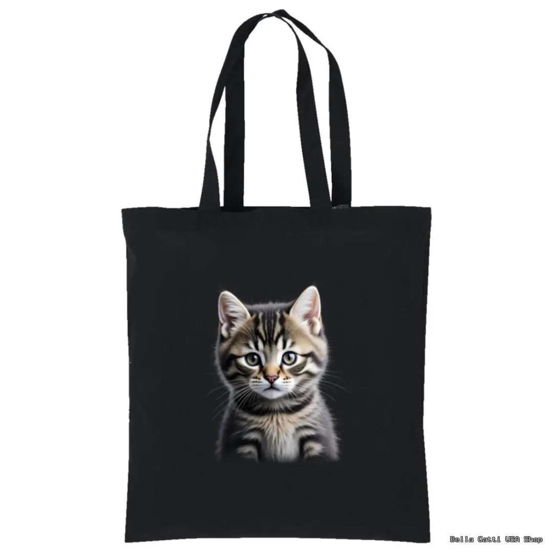A black tote bag with two handles features a realistic print of a gray tabby kitten with white markings, bright eyes, and perky ears centered on the front. The background is plain, making the kitten the focus of the design.