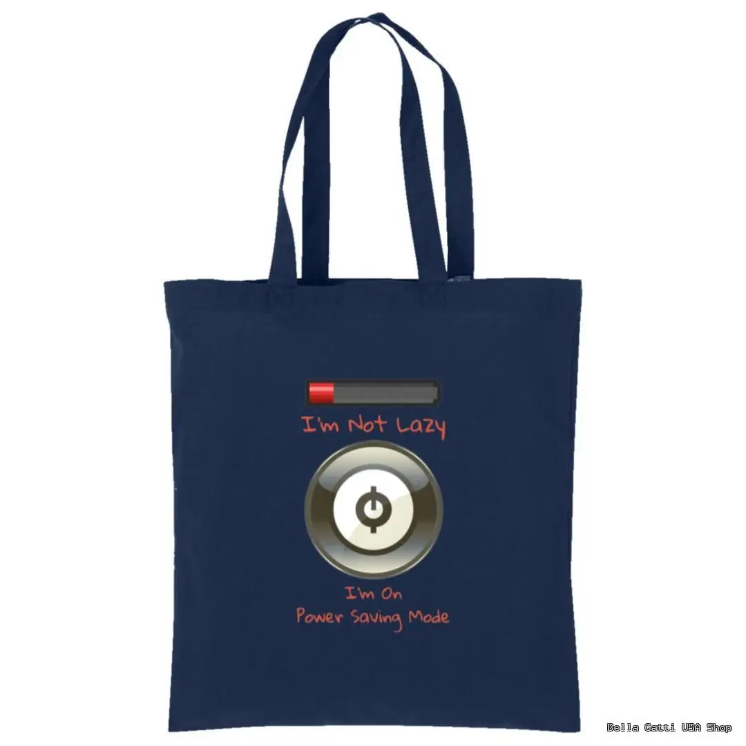 A navy blue tote bag with two handles. The front displays a low battery icon above the text Im Not Lazy in red, and a large power button icon below with the text Im On Power Saving Mode in orange. The bottom corner has small white shop branding.