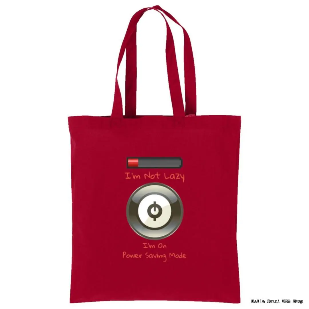 A red tote bag features an illustration of a nearly empty battery above a power button icon. Above the battery, text reads Im Not Lazy, and below the button, it says Im On Power Saving Mode in playful fonts.