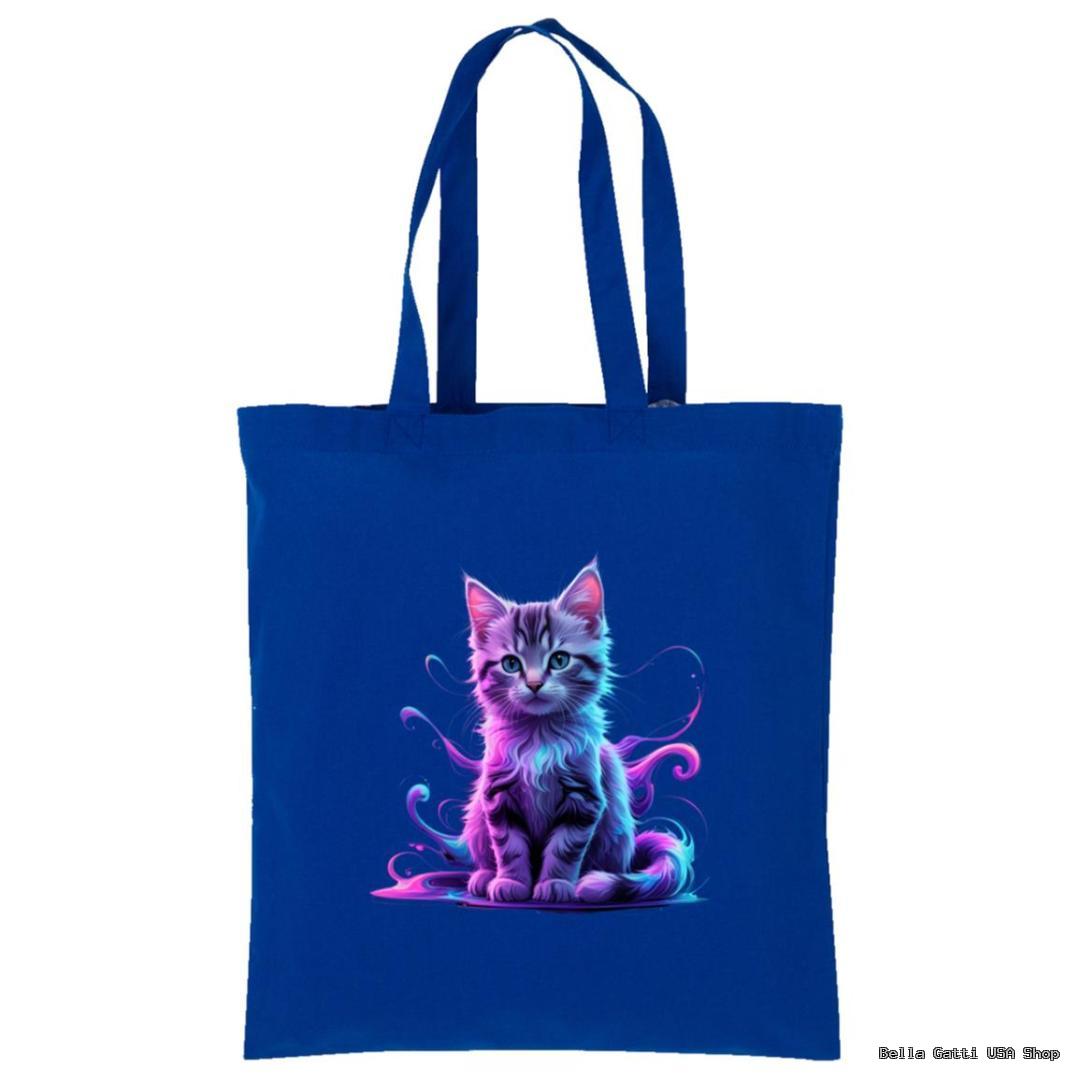 A royal blue tote bag features an illustrated, fluffy gray kitten with blue and purple lighting effects, sitting in the center. The kitten looks forward, surrounded by swirling neon accents, giving a magical, whimsical appearance.