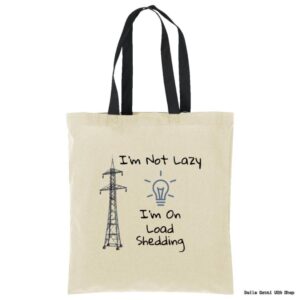 A beige tote bag with black handles features a drawing of an electricity pylon and a light bulb. Text reads: “I’m Not Lazy, I’m On Load Shedding.” The design humorously references power outages.