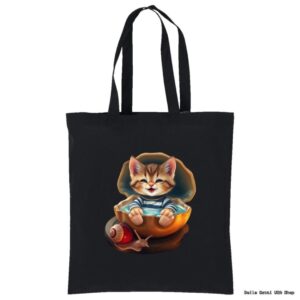 A black tote bag features a cute illustration of a smiling kitten sitting inside a cracked eggshell, wearing a blue-and-white striped shirt. A small snail rests nearby on the ground. The image is centered on the tote bag.