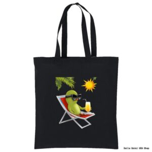 A black tote bag features a cartoon green bird wearing sunglasses, lounging on a red-and-white deck chair under a leafy branch and a yellow sun, holding a drink with a straw and orange slice.