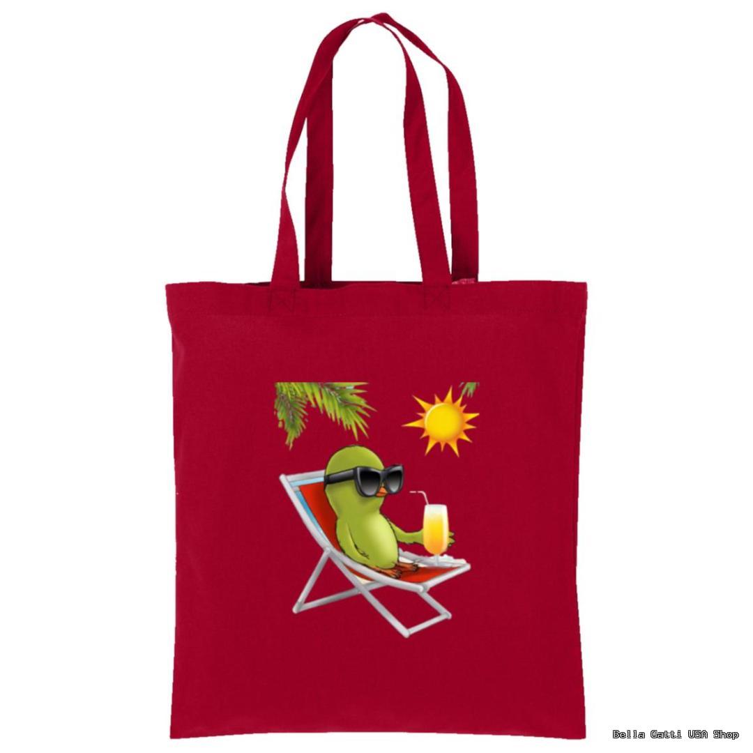 A red tote bag features an illustration of a relaxed green avocado wearing black sunglasses, sitting on a lounge chair under a palm branch with a bright yellow sun overhead, holding a glass of juice.