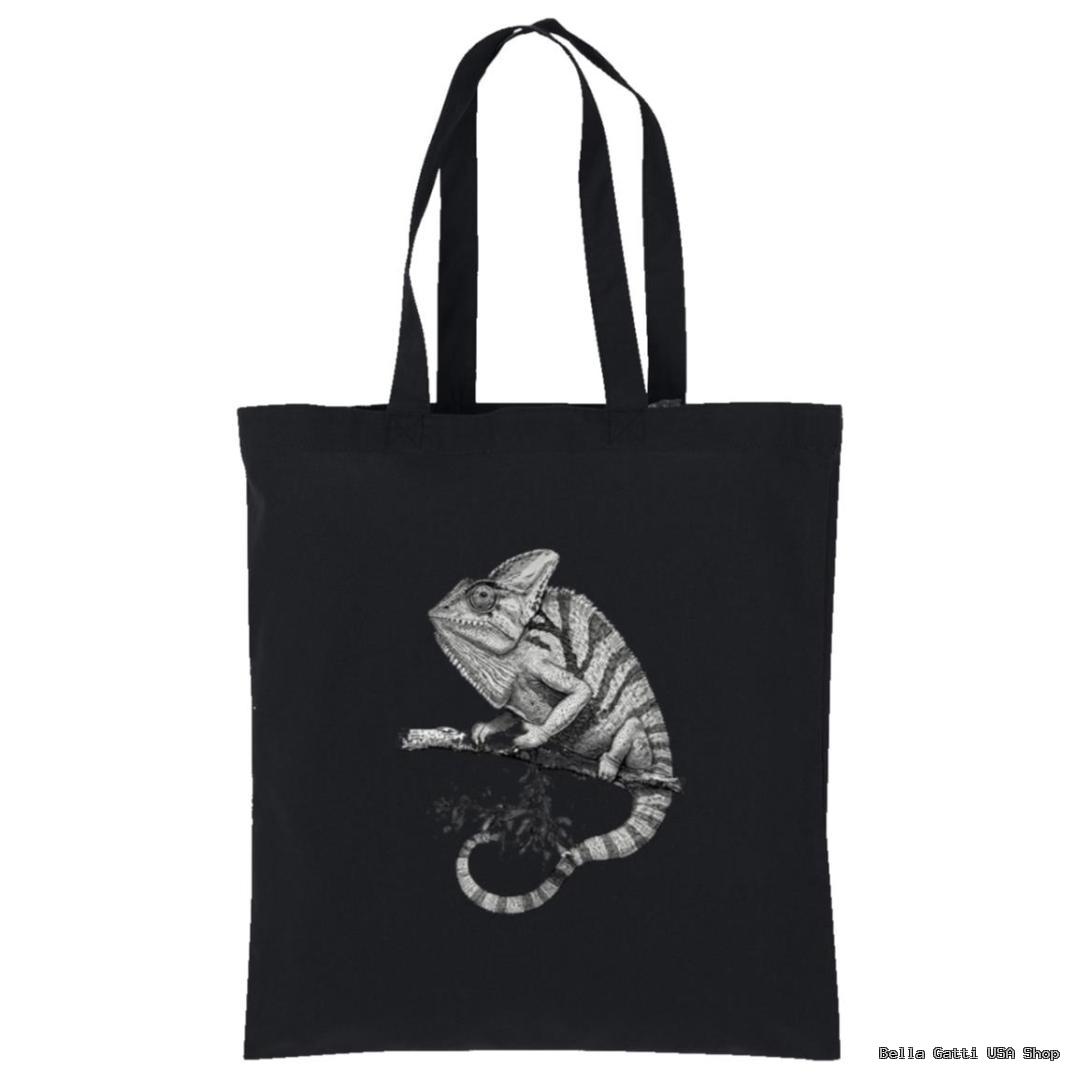 A black tote bag features a detailed grayscale illustration of a chameleon perched on a branch. The chameleon is facing left, and its curled tail and textured skin stand out against the dark background.