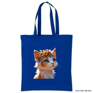 A royal blue tote bag features an illustration of a cute, fluffy kitten wearing a colorful flower crown. The kitten looks upward with bright, expressive eyes. The bag has two handles and is set against a white background.
