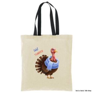A beige tote bag with black handles features an illustration of a turkey wearing a blue scarf. Next to the turkey, the words Cold TURKEY are written in blue and orange playful fonts. The background is plain.