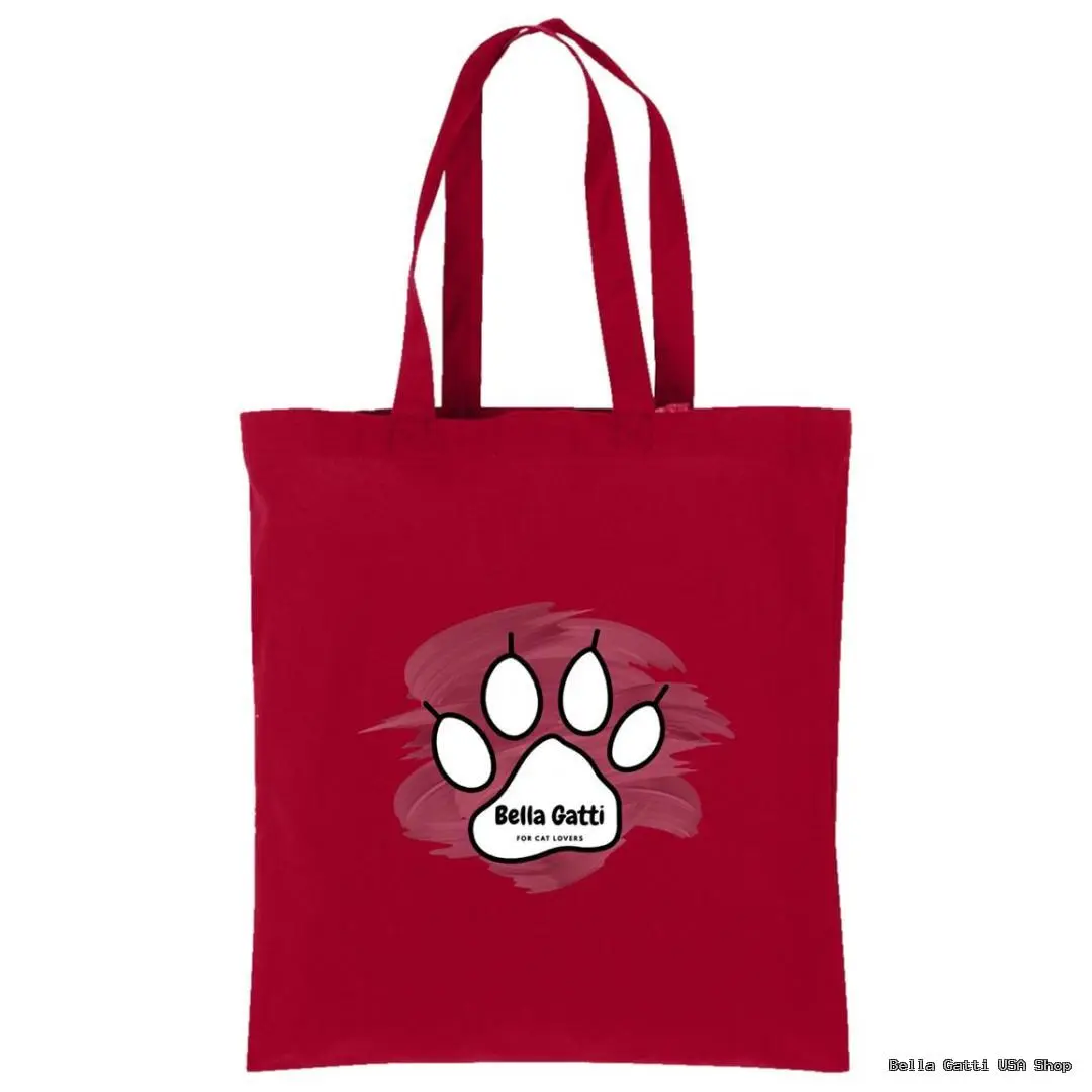 A red tote bag with long handles features a large white cat paw print graphic at the center, outlined in black. Inside the paw print, it says “Bella Gatti” in bold text, above smaller text that reads “for cat lovers,” all over a light red paint splash.